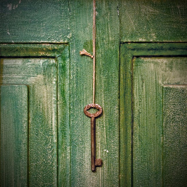 Weathered rusty metal key hanging on rope on shabby green wooden door of house